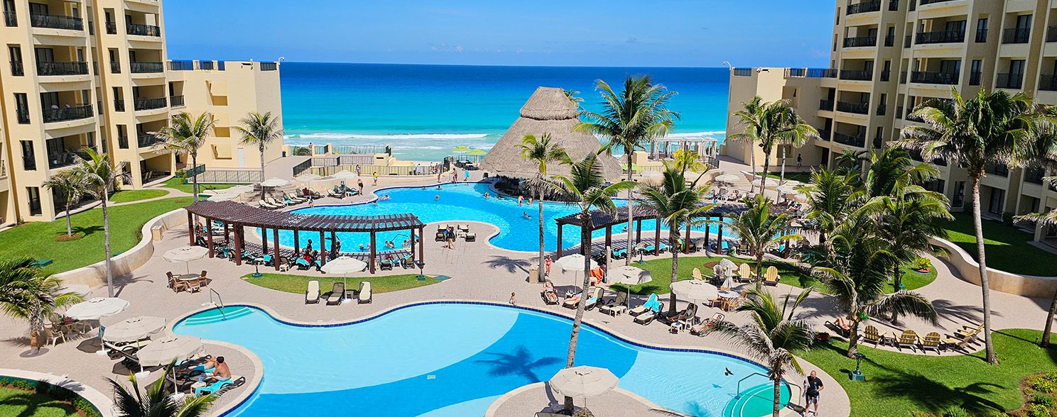 Resort pools and palm-shaded gardens between hotel wings